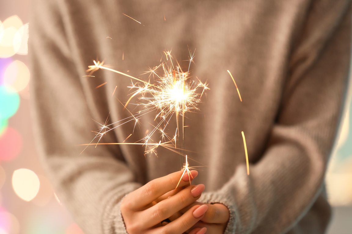 Woman with Sparkler against Blurred Lights